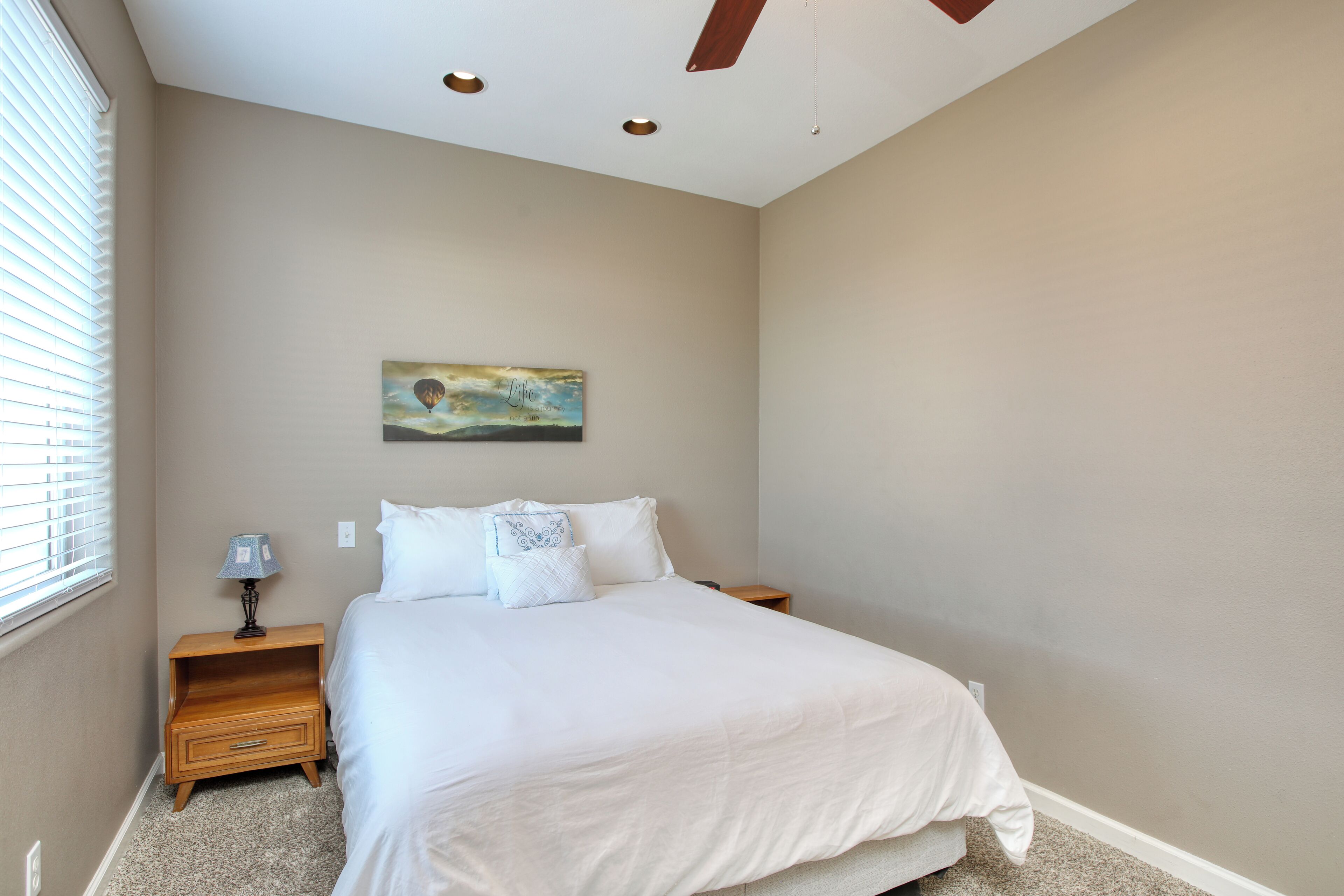 A bedroom with a bed, a nightstand, a lamp, and a painting on the wall.
