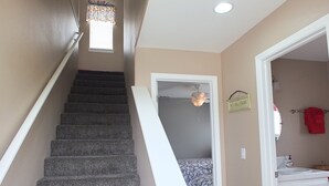 A staircase leading to a bedroom with a bed, a ceiling fan, and a bathroom with a sink and towel rack. - 618 Airpark: 2  BR, 2  BA Condominium in Oceano, Sleeps 4 (Oceano)