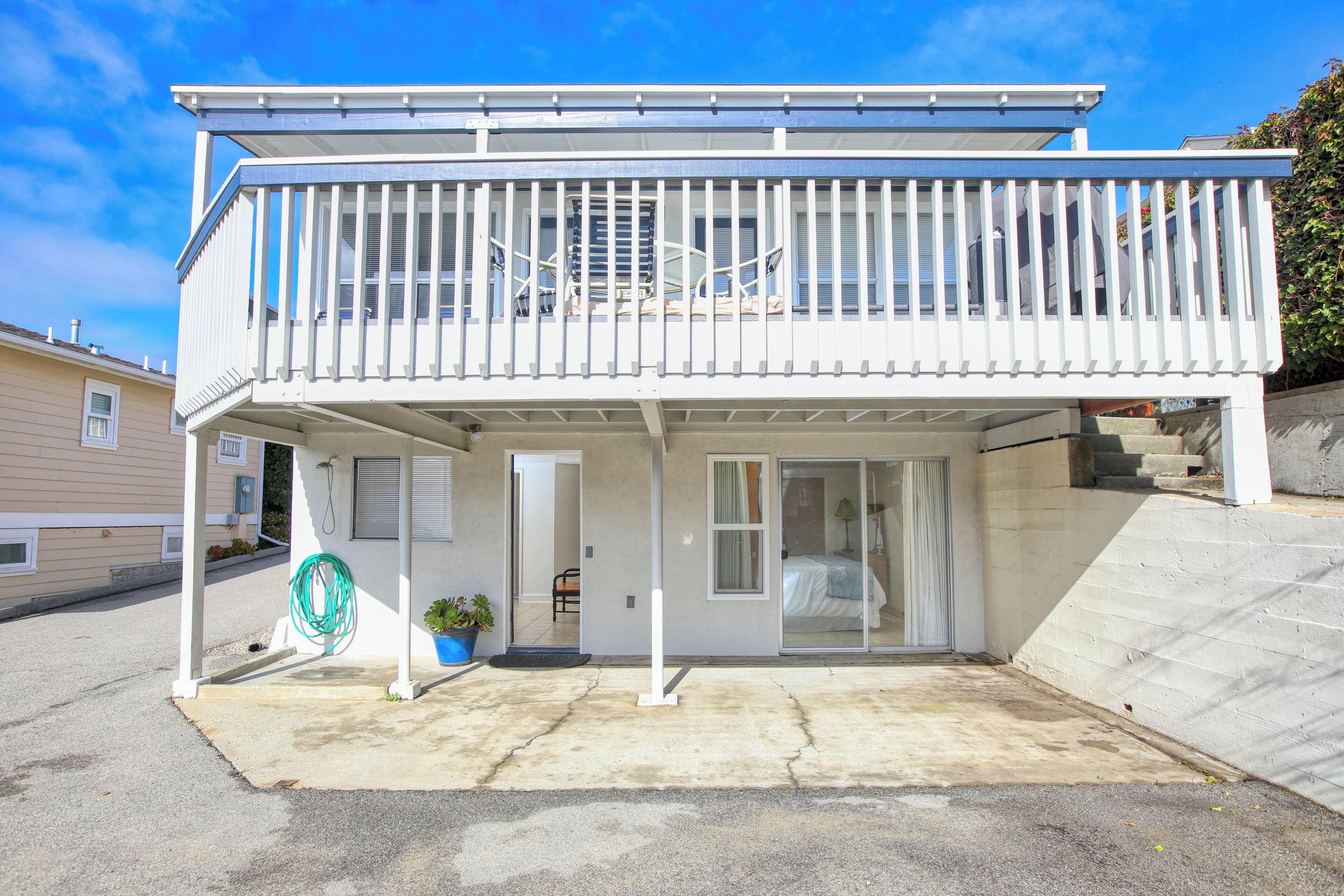 A two-story building with a balcony, a covered patio, and a sliding glass door leading to a bedroom.