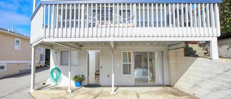 A two-story building with a balcony, a covered patio, and a sliding glass door leading to a bedroom.