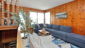 A living room with a blue sofa, wooden walls, a staircase, and a potted plant. - 141 A 1st Street: 3  BR, 2  BA House in Avila Beach, Sleeps 6 (Avila Beach)
