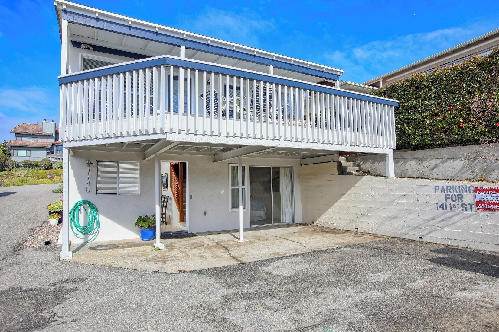 A two-story building with a balcony, a covered entryway, and a parking sign.