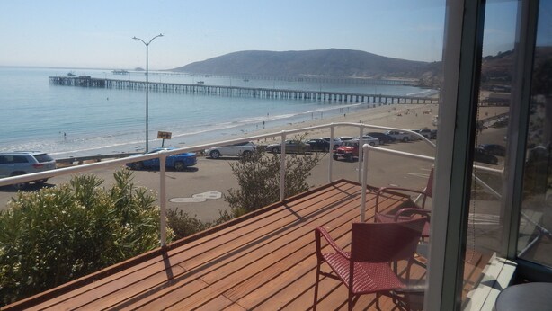 Une vue depuis un balcon donnant sur une plage, avec une jetée qui s’avance dans l’eau.