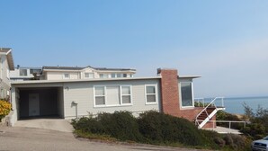 Une maison moderne à deux étages, dotée d’un garage, d’une cheminée en briques et d’un escalier menant à l’étage supérieur.