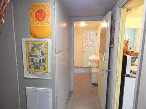 A hallway with a refrigerator, a poster, and a door leading to a bathroom.