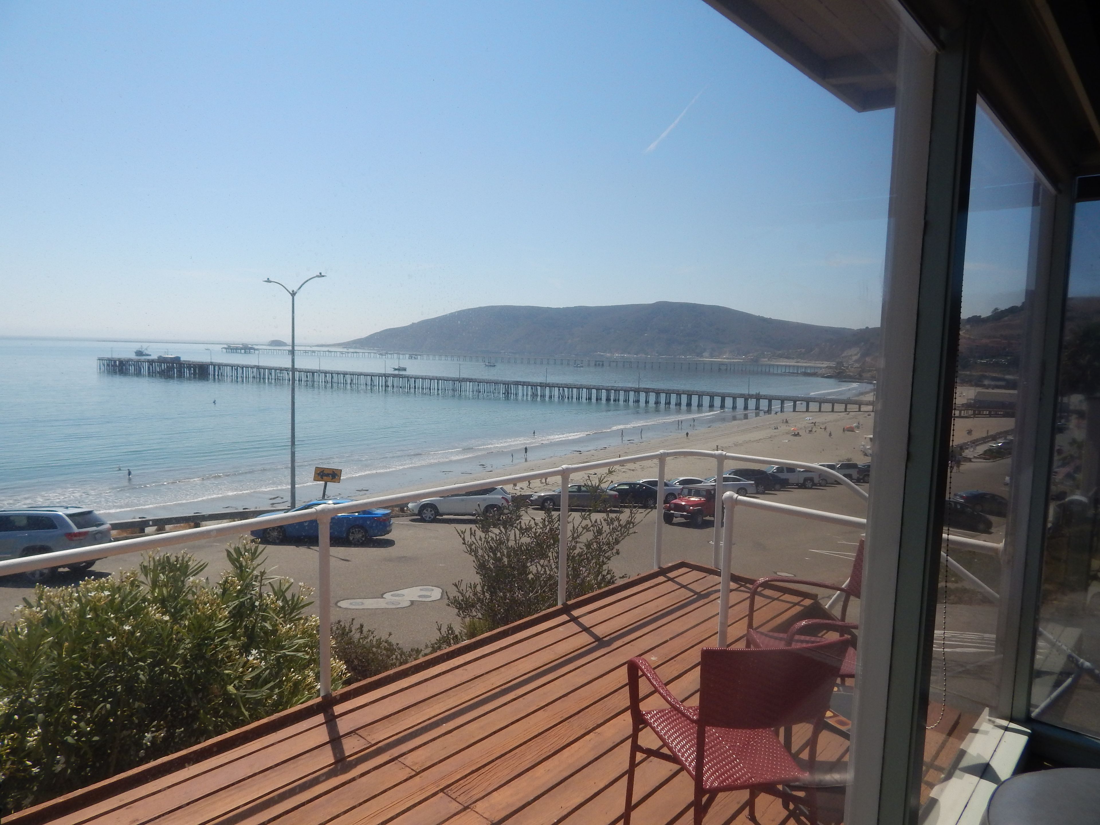 A view from a balcony overlooking a beach with a pier extending into the water.