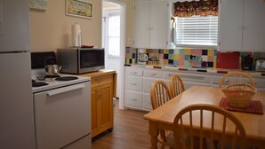 A kitchen with white cabinets, a microwave, a stove, and a dining table with chairs.
