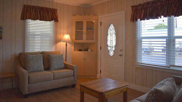 A living room with a sofa, a coffee table, a cabinet, and a door with a window.
