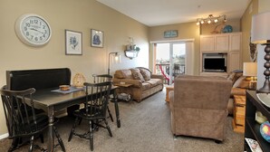 A living room with a dining table, chairs, a sofa, and a television. - 210 Casa Bella: 2  BR, 2  BA Condominium in Pismo Beach, Sleeps 6 (Pismo Beach)