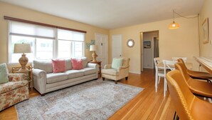 A living room with a sofa, armchairs, a dining table, and a rug. - 369 Stimson: 3 BR, 2 BA House in Pismo Beach, Sleeps 8 (Pismo Beach)