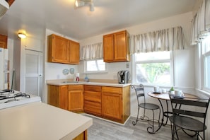 Kitchen area with a central island, coffee maker, and seating for two.