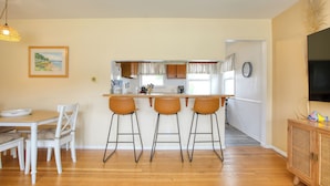 A kitchen with a bar area, wooden flooring, and a dining table with chairs. - 369 Stimson: 3 BR, 2 BA House in Pismo Beach, Sleeps 8 (Pismo Beach)