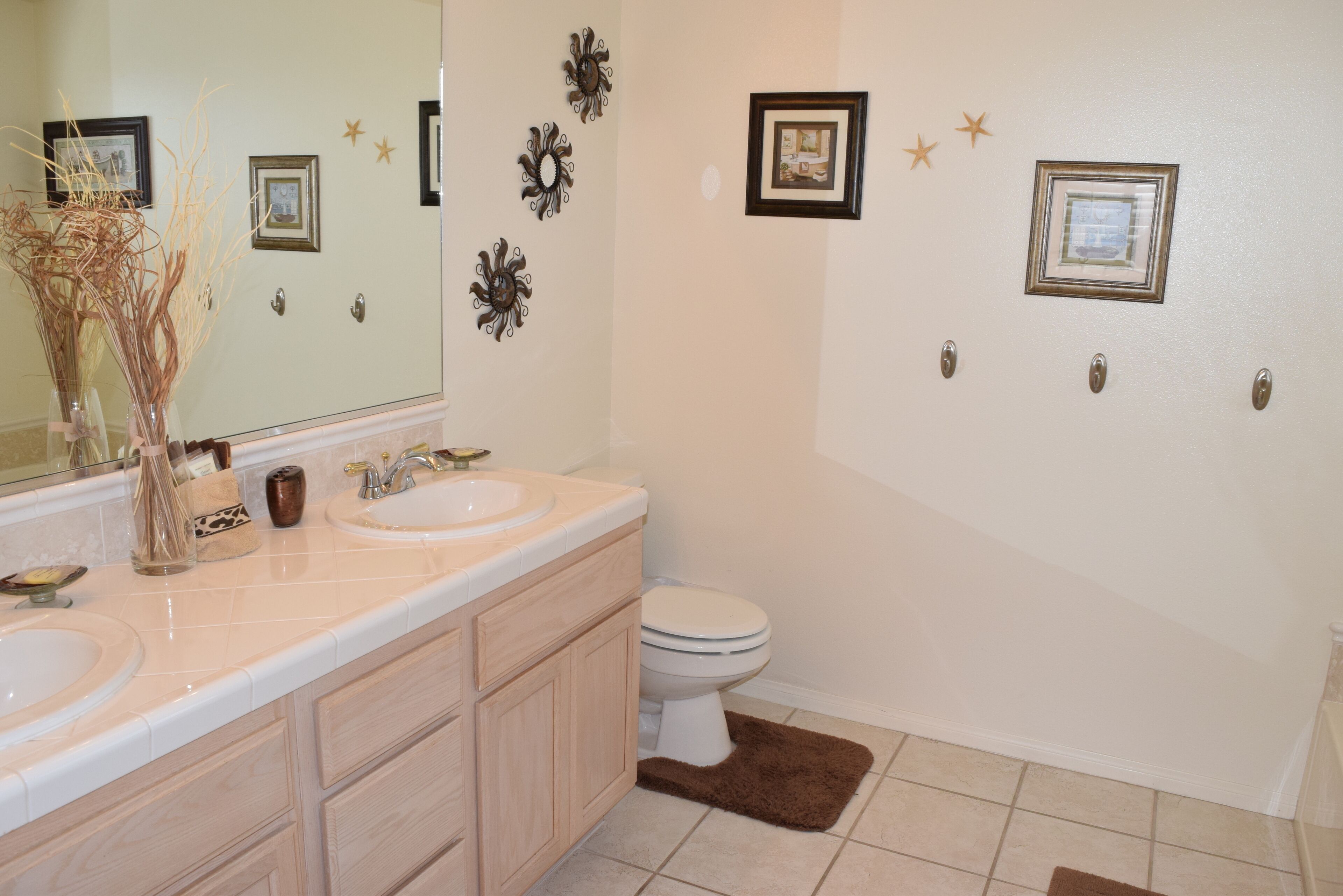 Une salle de bain avec deux lavabos, des toilettes et des éléments décoratifs sur les murs.