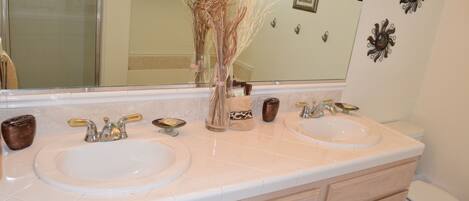 A bathroom with two sinks, a mirror, and a toilet.