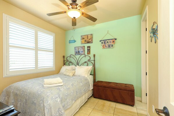 A bedroom with a bed, a ceiling fan, a window with blinds, and a wall with a 'Beach Club' sign. - 236 Ocean View Avenue (Pismo Beach)