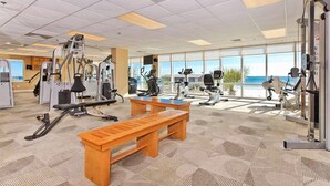 A gym with cardio machines, weight stations, and a wooden bench. - Seawind 403: Updated, child friendly Beachfront, Best location in Gulf Shores (Gulf Shores)