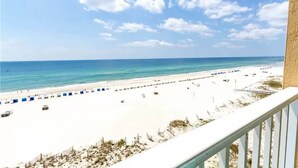 A beach view from a balcony with a clear sky, sandy beach, and a few umbrellas. - Seawind 403: Updated, child friendly Beachfront, Best location in Gulf Shores (Gulf Shores)