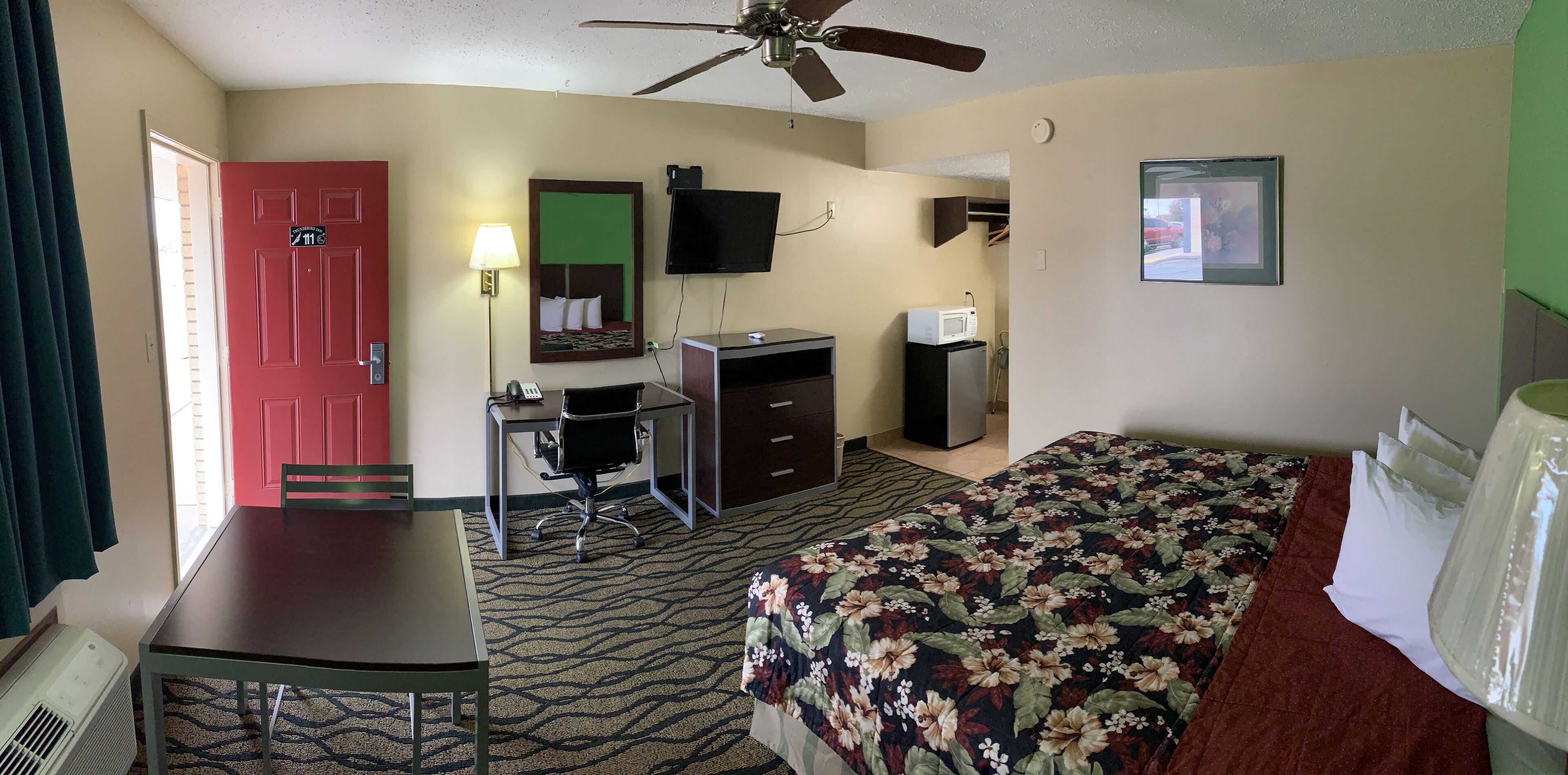 Una habitación de hotel con cama, escritorio, silla y televisor.