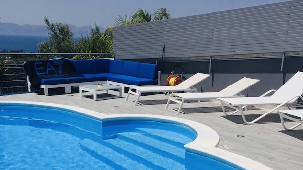 A swimming pool with lounge chairs and a blue sofa.
