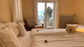 A hotel room with two beds, a chair, a radiator, and a view through a glass door. - Holiday house with 2 bedrooms, terrace and balcony, 150 m² (Inzell)