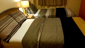 Ein Hotelzimmer mit zwei Betten, jeweils mit gestreifter Bettwäsche und einem Nachttisch mit Lampe.