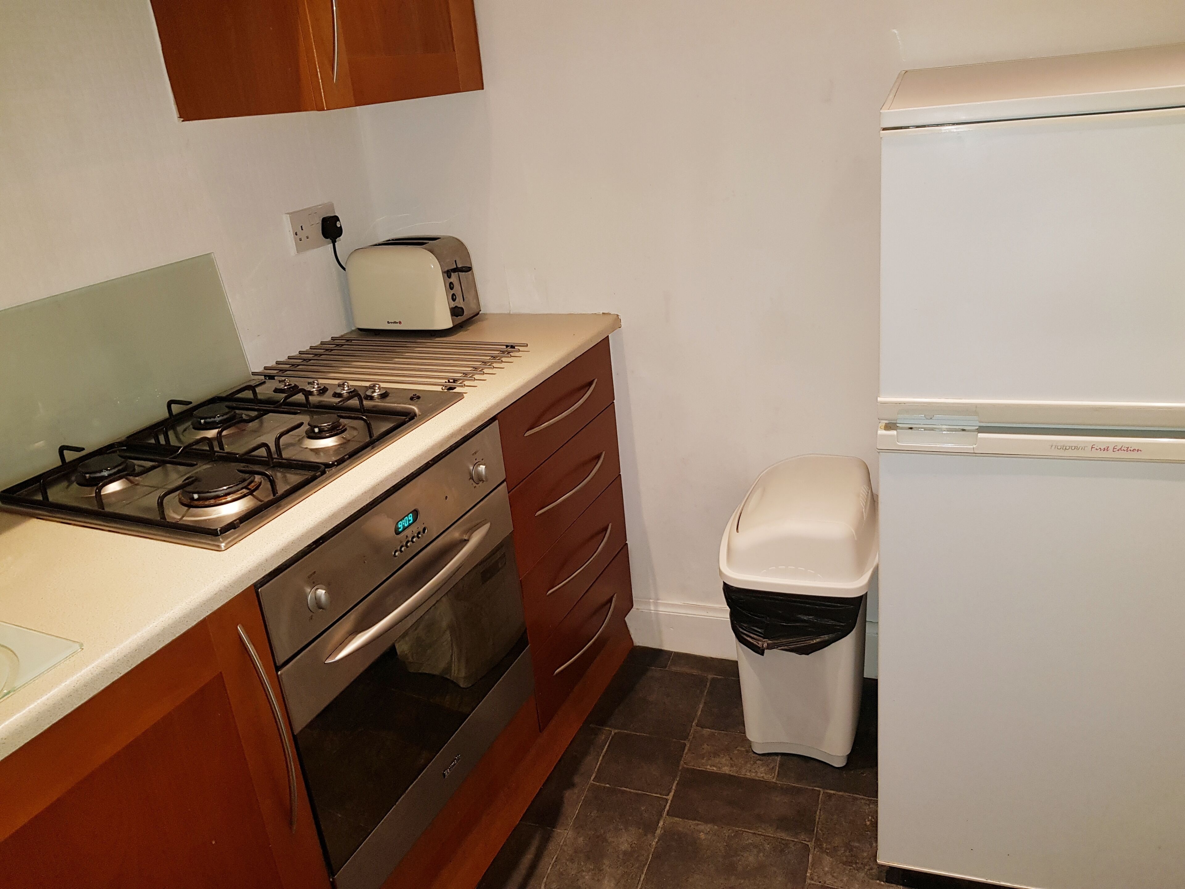 Een keuken met een gasfornuis, oven en een witte koelkast.