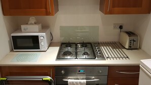 Eine kompakte Küche mit Mikrowelle, Toaster, Gasherd und Backofen.