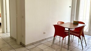 Een eetruimte met een tafel, stoelen, een deur en een betegelde vloer.
