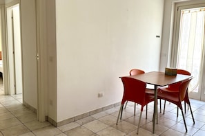 A dining area with a table and chairs, a door, and a tiled floor.