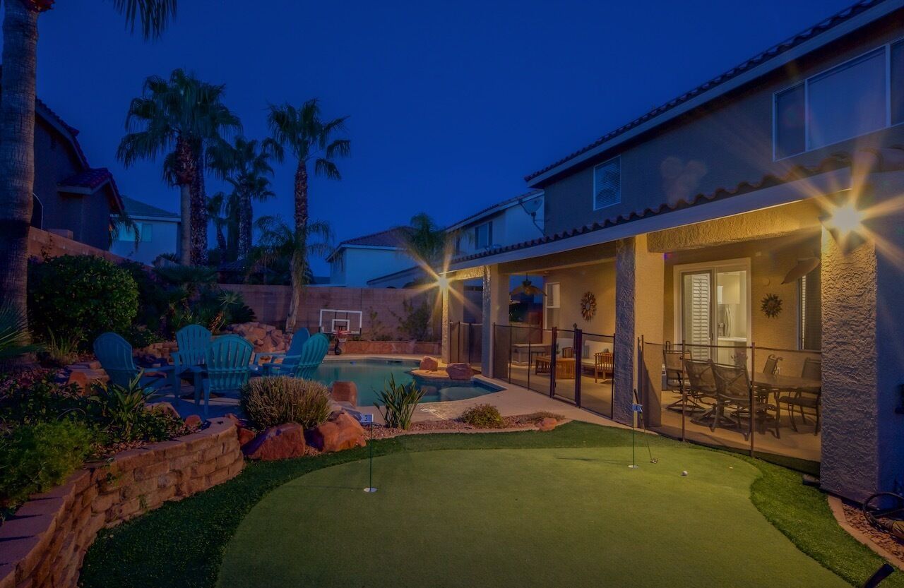 A residential property with a swimming pool, patio furniture, and a well-maintained lawn.