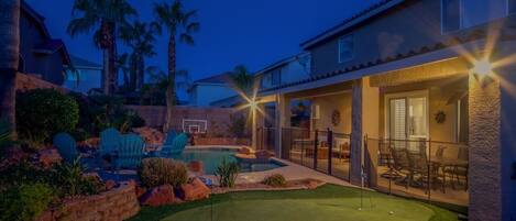 A residential property with a swimming pool, patio furniture, and a well-maintained lawn.