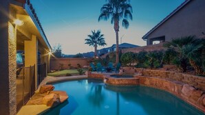 Une piscine avec un jacuzzi, des palmiers et du mobilier d’extérieur.