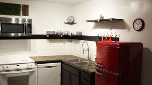 Une cuisine compacte équipée d’un four à micro-ondes, d’une cuisinière, d’un lave-vaisselle et d’un réfrigérateur rouge.