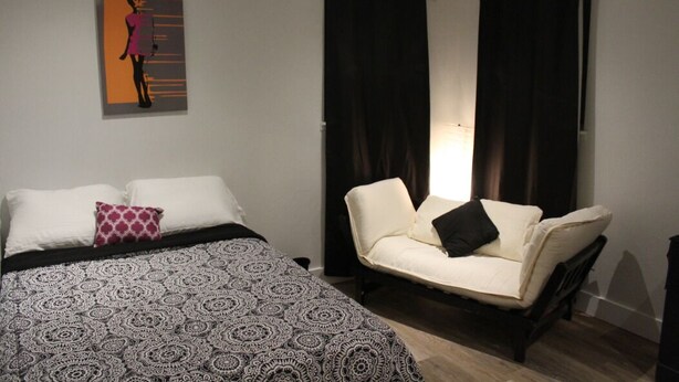 Une chambre à coucher avec un lit, deux oreillers, une chaise et une œuvre d’art murale.