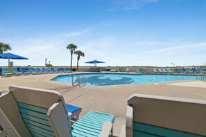 A pool area with lounge chairs and umbrellas, surrounded by palm trees.