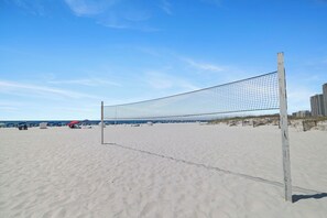 A beach volleyball net on a sandy beach with a clear sky.