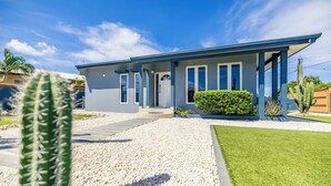 A modern two-story house with a blue exterior, a covered porch, and a well-maintained lawn.