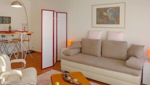 Un salon avec un canapé, une table à manger et des chaises, une lampe et un tableau au mur.