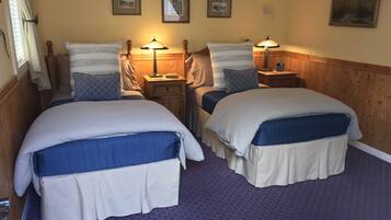 A double room with two beds, a wooden headboard, a nightstand with a lamp, and a framed picture on the wall.