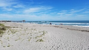 A beach with a pier in the background, sandy shore, and clear skies. - Family Fun! Steps to beach and Pier, Heated pool, hot tub, surf/bike/beach gear (Cocoa Beach)