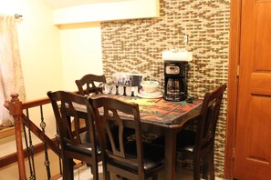 A dining area with a table set for four, a coffee maker, and a patterned tablecloth. - East 42nd Mansion (Brooklyn)
