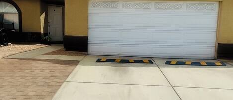 A residential garage with a white garage door, a tiled roof, and a concrete driveway.