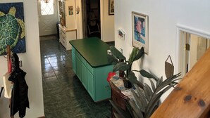 Una cocina amplia con una isla verde, un comedor con mesa y un pasillo que lleva a un dormitorio.
