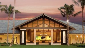 Um resort com um amplo saguão, palmeiras e vista para o pôr do sol.