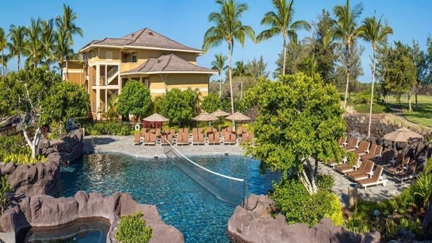 Um resort com piscina, espreguiçadeiras e palmeiras.
