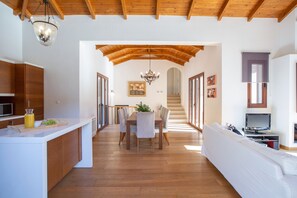 Un vaste espace de vie comprenant une table à manger, un canapé et un escalier menant à un autre niveau.
