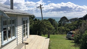 A house with a wooden deck, a chimney, and a view of the ocean.