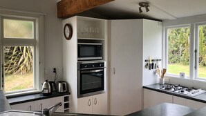 A modern kitchen with a built-in oven, microwave, and gas stove. There is a window with a view of greenery outside.