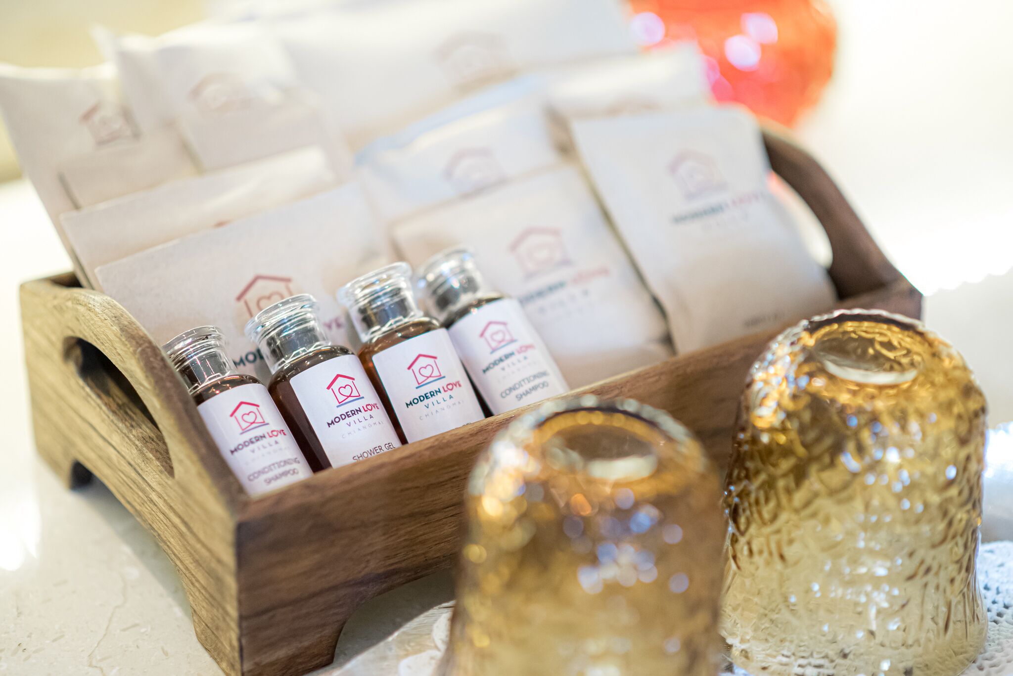 A wooden tray with bottles of shower gel and a golden bottle.