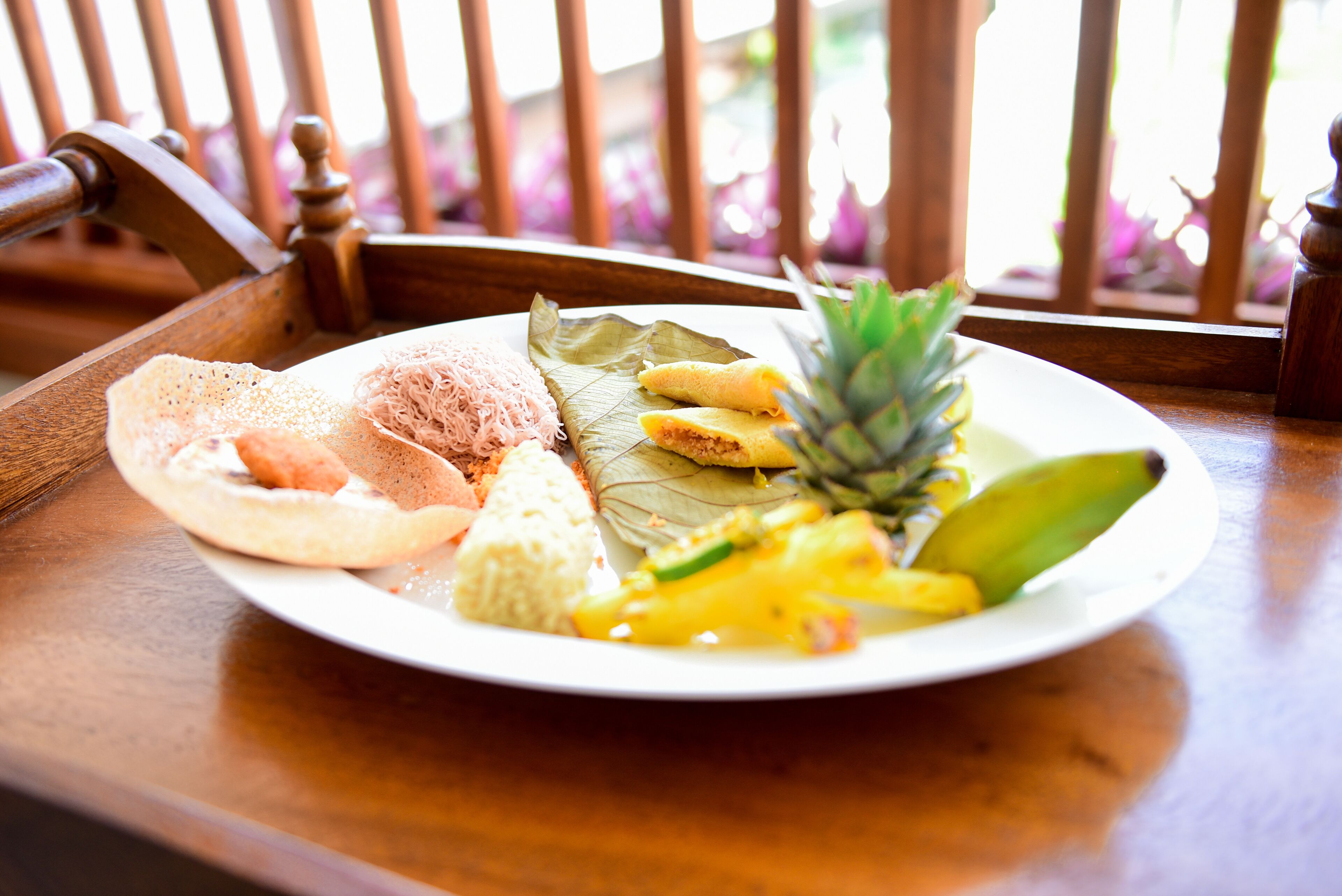 A plate of food with a banana, pineapple, and other items on a table.